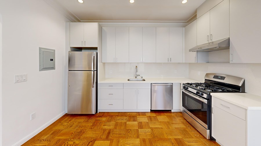 A kitchen with white cabinets and a wooden floor.
